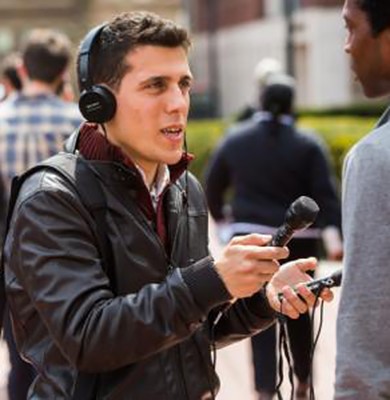 man with headphones holding mic and digital recording device
