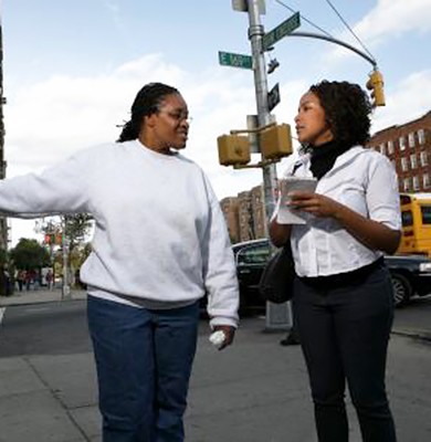 one woman interviewing another woman on a street corner