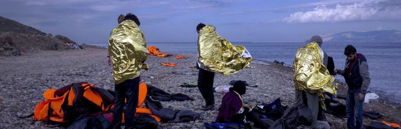 a handful of refugees wearing blankets after coming ashore in Greece