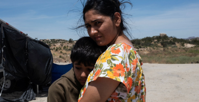 Woman hold her child, desert background. 