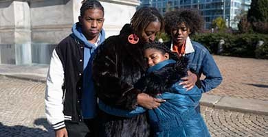 woman hugging child with two other children next to her