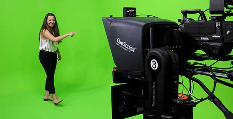 Woman gesturing in front of camera with green screen in background