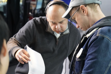 Two men reading a piece of paper. 