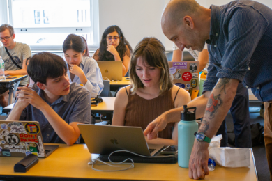 Professor interacting with students at a laptop computer. 