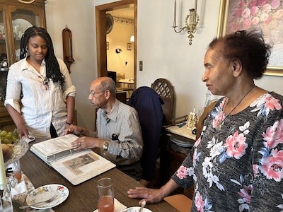 Three individuals looking through a book.