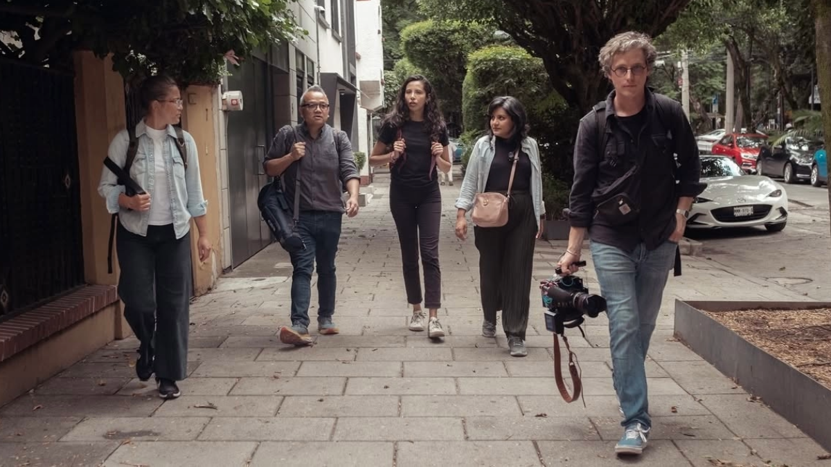 Five individuals walking down a sidewalk. 