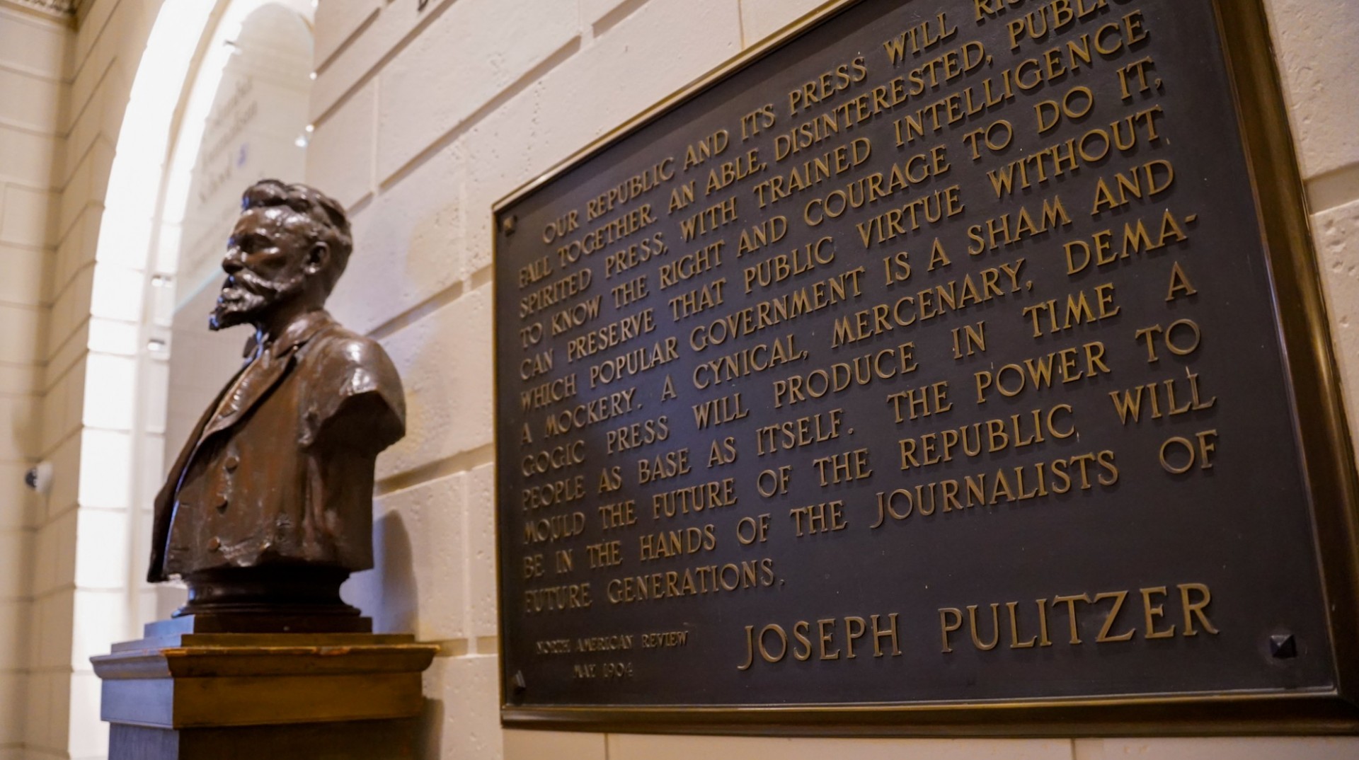 Bust of Joseph Pulitzer next to a quote of his from the early 1900s printed on a plaque. 