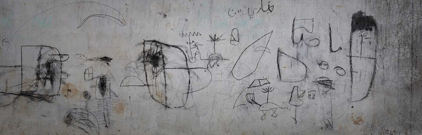 Photo image of children’s drawing on a wall showing helicopters and other shapes
