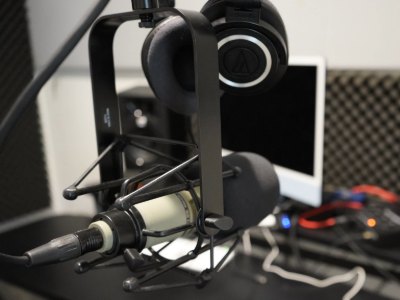 Headphones resting on a mic stand in a recording booth.