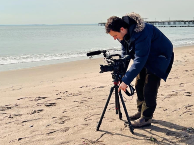 Cameraman filming on a beach.