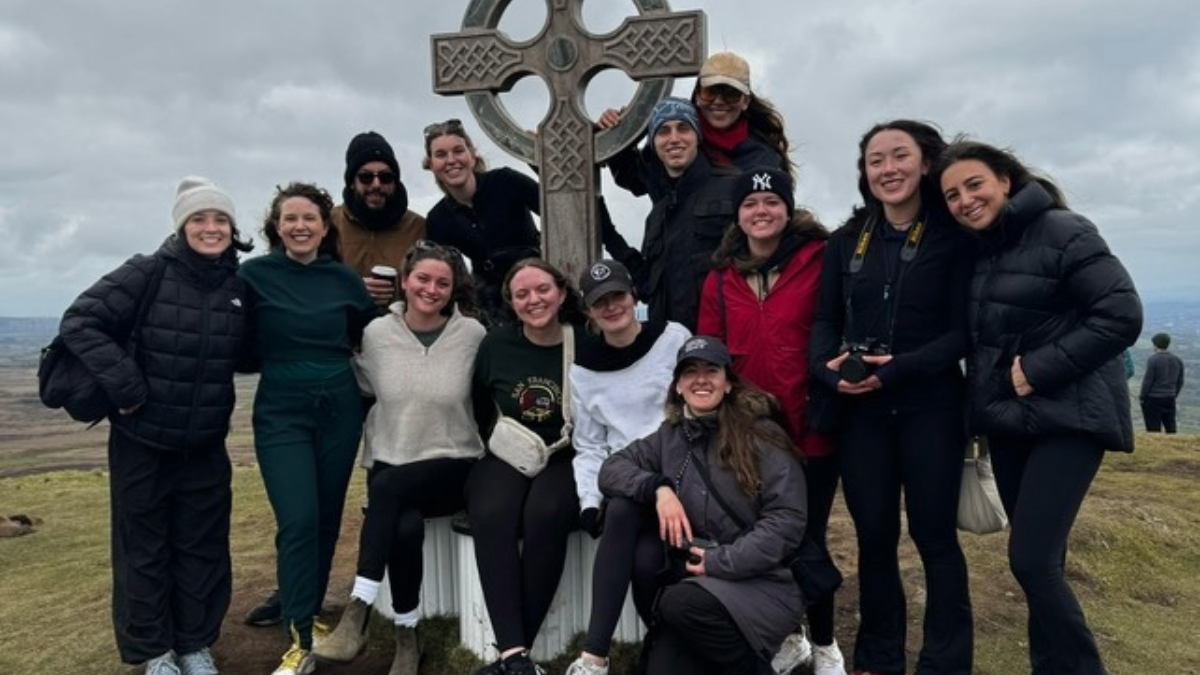 Students gathered around a stone cross. 