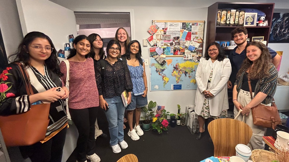 Students gather for a photo in front of a map of the world. 