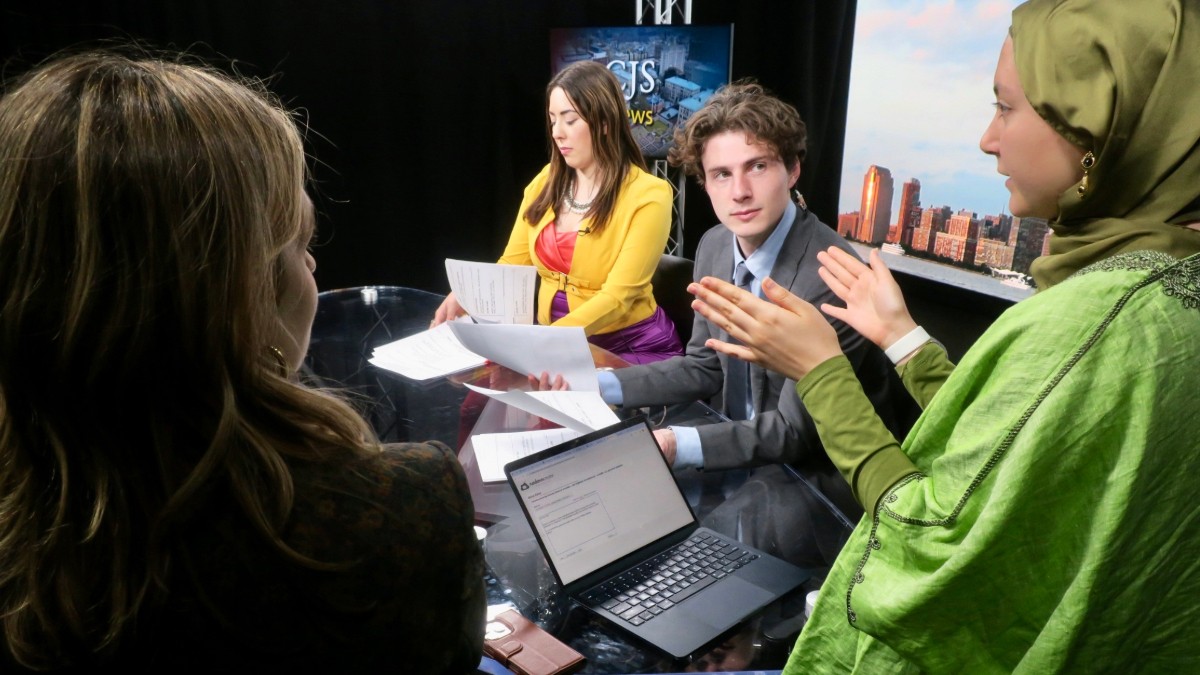Students gather around a newsdesk. 