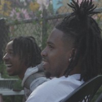 Two young men laugh besides each other in a backyard.