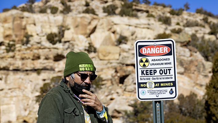 From the 2023 Tobenkin Award winning series from the Center for Public Integrity, Earl Tulley beside a sign warning the unsuspecting of the invisible danger at the Claim 28 abandoned mine in Blue Gap, Arizona, in the Navajo Nation. (Daniel A. Anderson) Earl Tulley beside a "keep out" sign