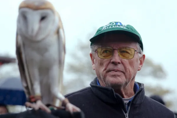 Man wearing a hat holding an owl.