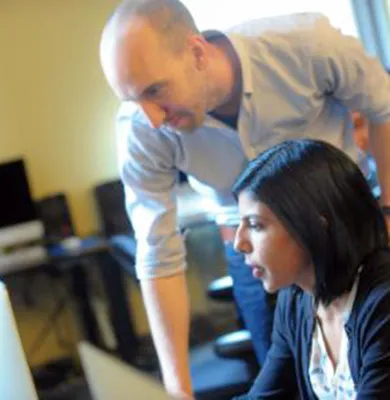 professor leaning over a student at a computer