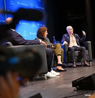A panel discussion with a camera recording. 