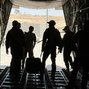 Soldiers walking out of a cargo plane. 