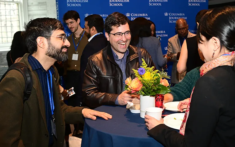 CJS alumni in conversation at a table with a floral centerpiece. 