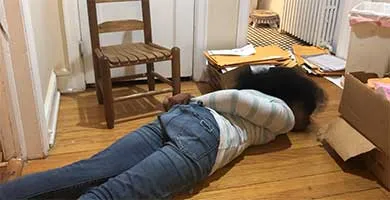 girl lying face down on the floor with her hands behind her back to demonstrate restraints she endured at a school 