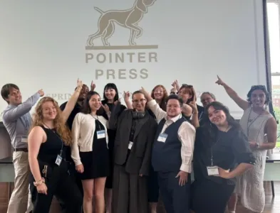 Columbia Publishing Course students taking a group photo in front of a projector screen that reads "Pointer Press." (Credit: CPC)