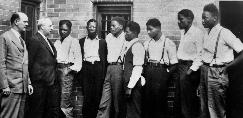 Black and white photo of 2 white men and 7 black teenagers