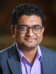 Headshot of Dhrumil Mehta with brown background. 