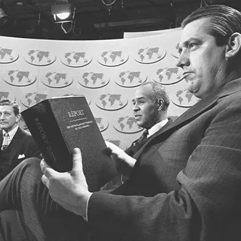 Photo from The Riot Report of a man holding a copy of the Kerner Commission Report. 