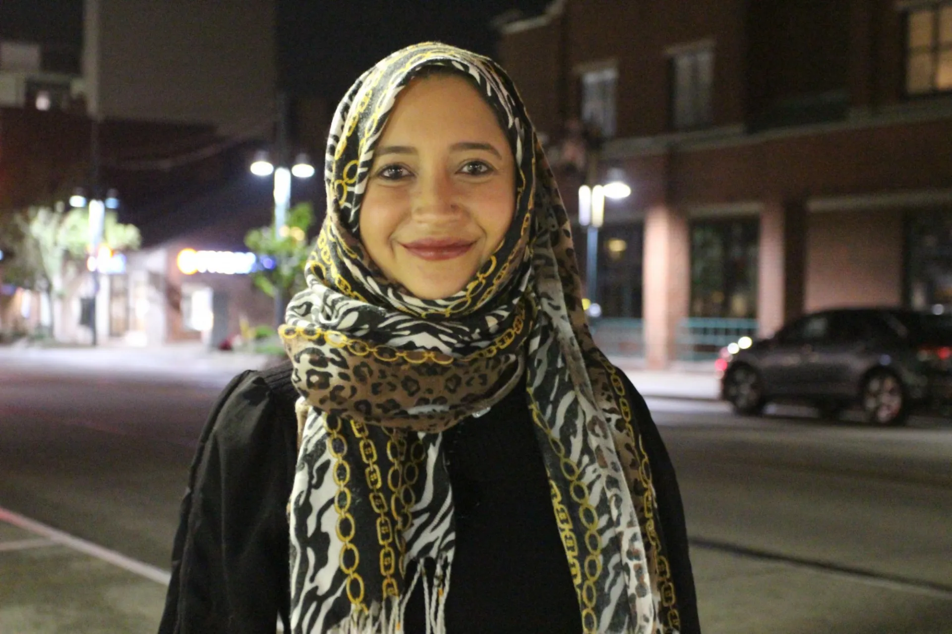 smiling woman in headcovering, outdoors at night