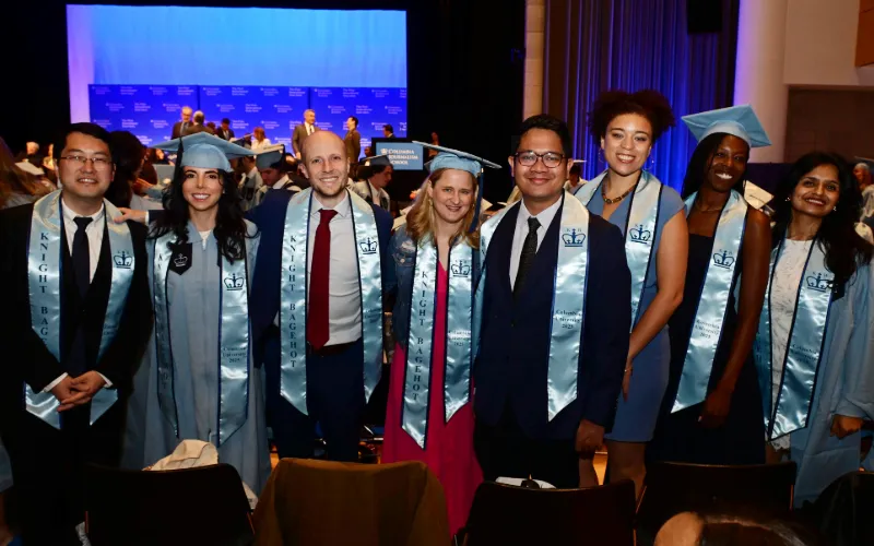 Group poses for picture in graduation regalia. 