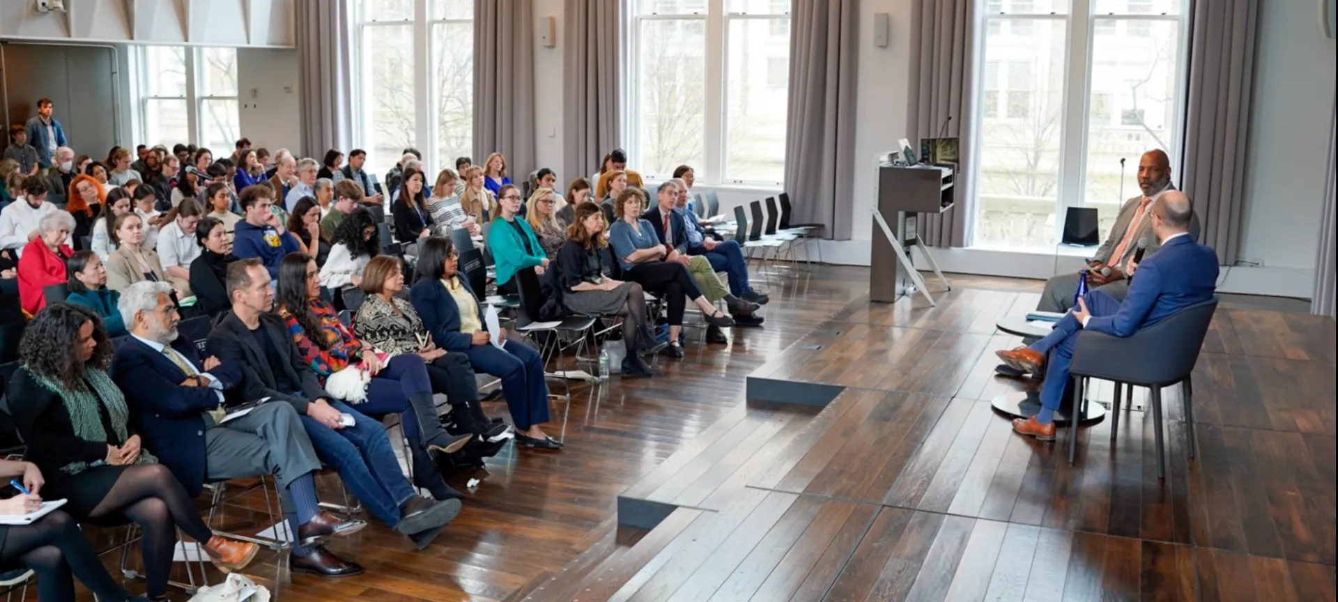 A two-person panel sits in front of a crowd. 