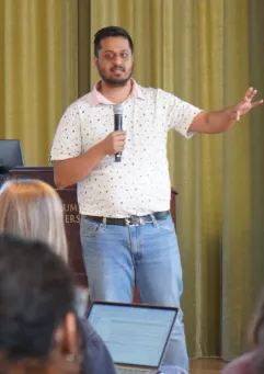 Meghnad Bose, '24 M.S. Data Journalism, standing and holding a microphone