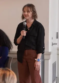 Lauren Watson, '24 M.S., standing and holding a microphone