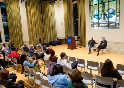 A two person panel speaks to an audience. 