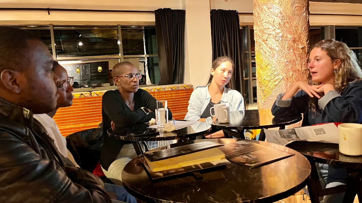 One male and four females sitting at a table and talking