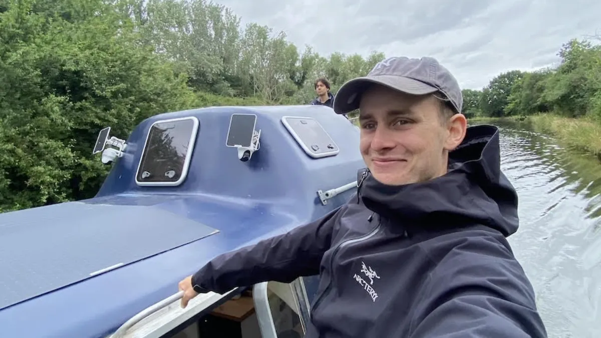 Johnny Sturgeon, '25 M.S. Documentary, on the blue houseboat he built before attending Columbia Journalism School. Another male is in the foreground.