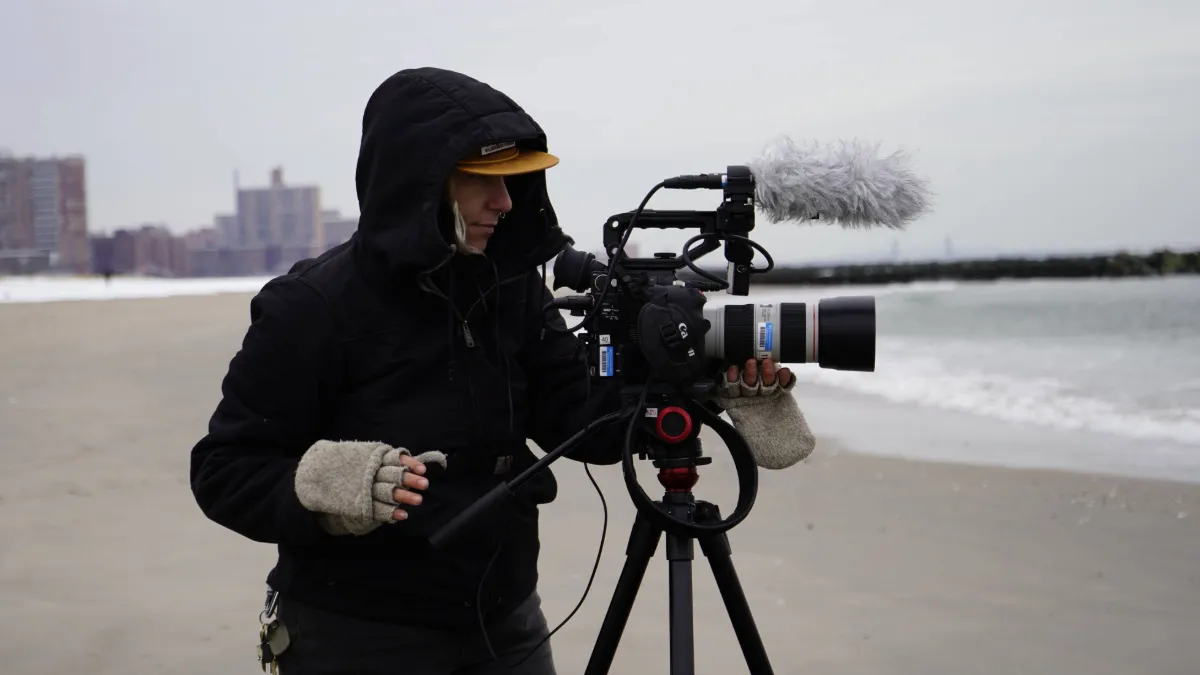 Student operating a camera on a beach during winter. 