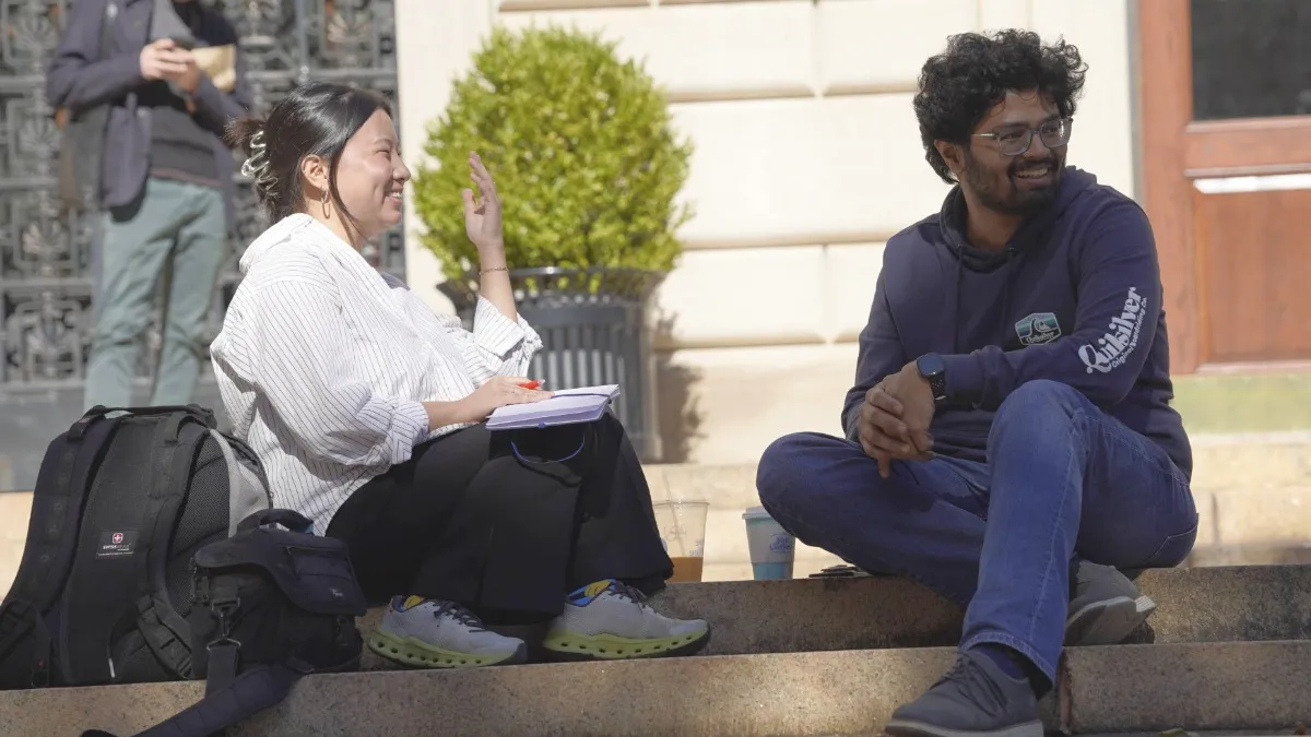 Two students sitting on the steps in front of Pulitzer Hall. 