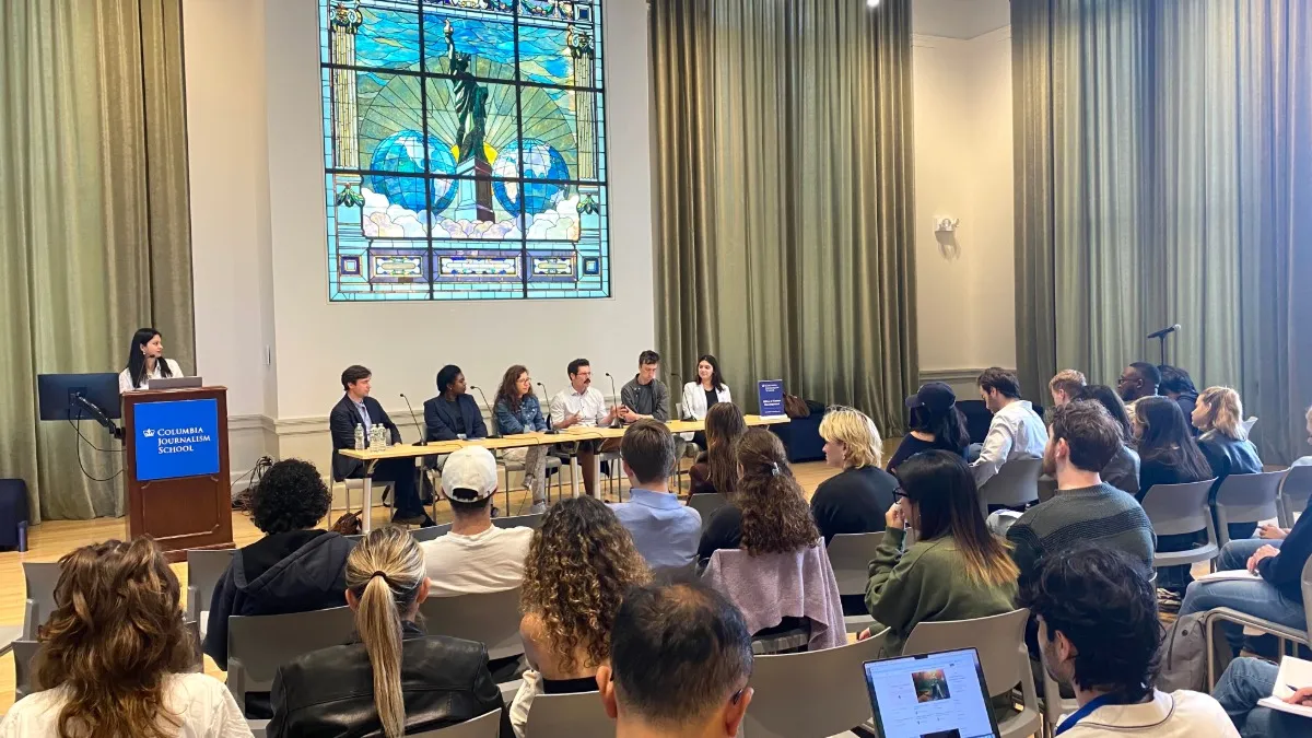 Students gathered in an event space listening to a panel discussion. 
