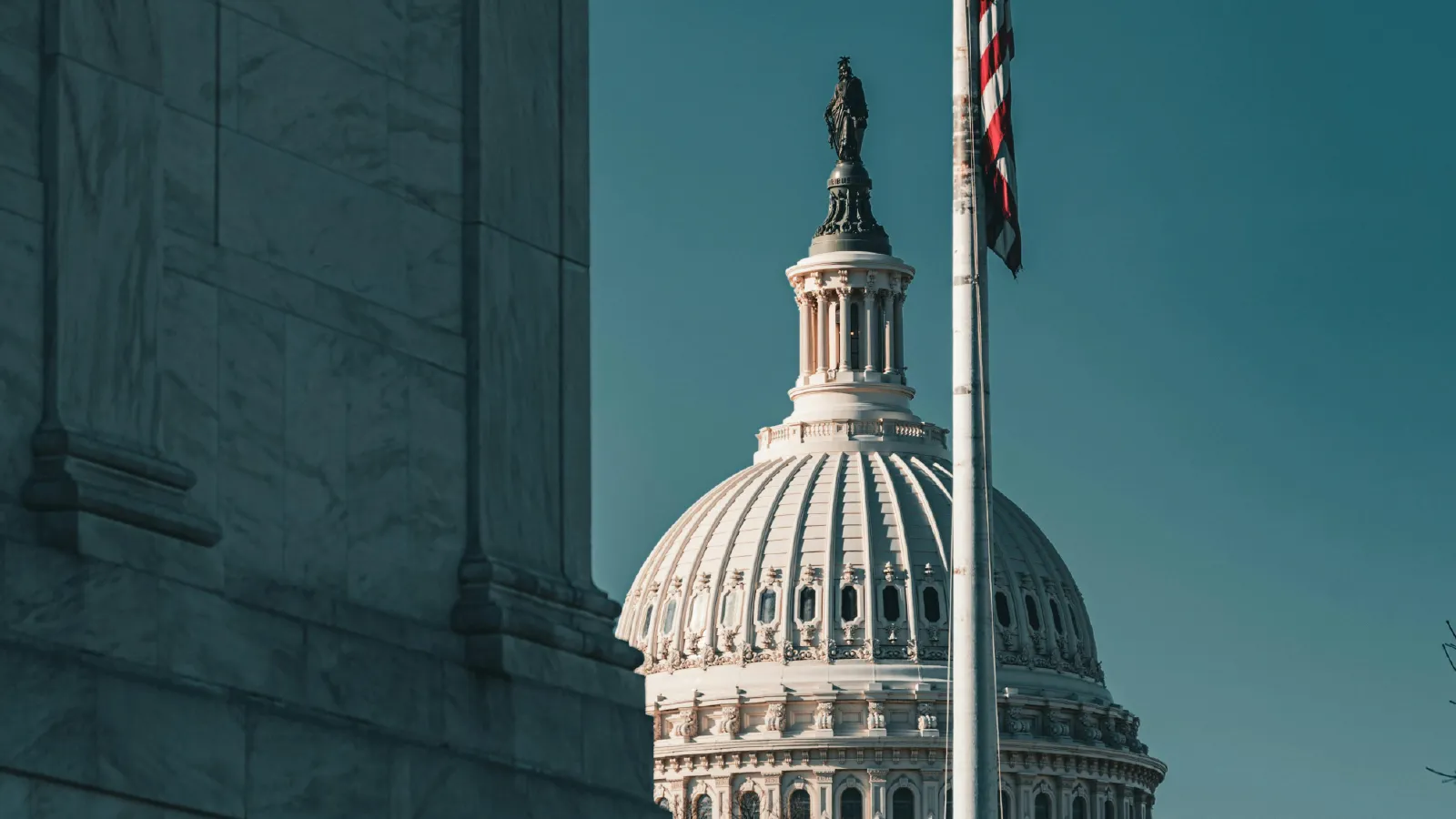 The U.S. capitol building with an American flag in the foreground. 