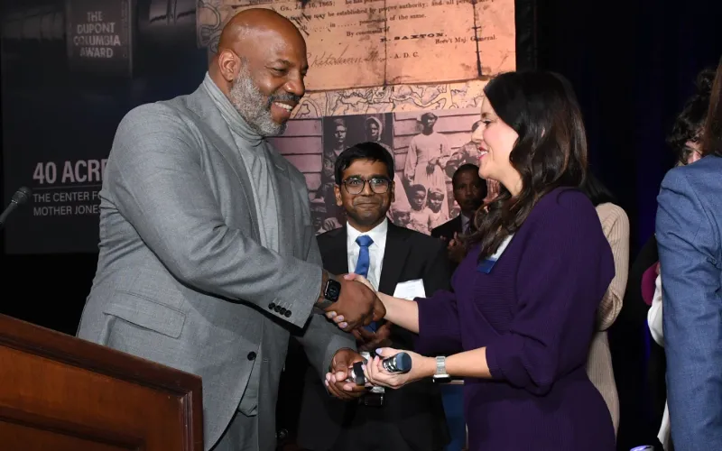 Man giving a prize to a woman during an award ceremony. 