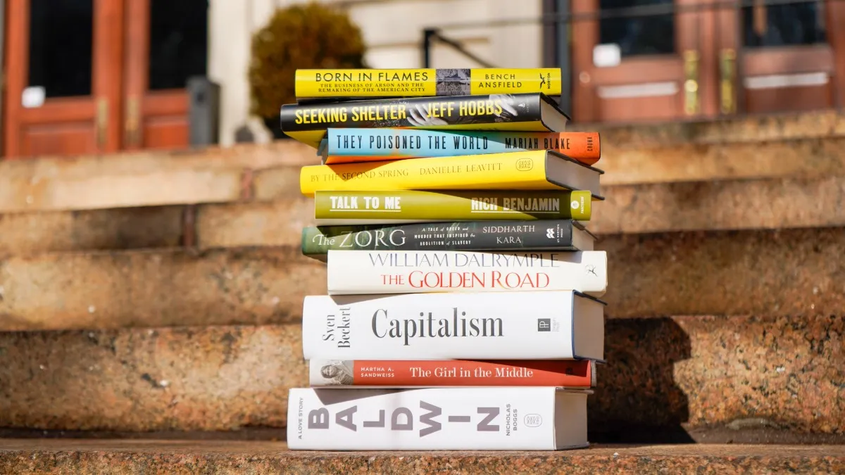 A stack of eleven books on outdoor steps.