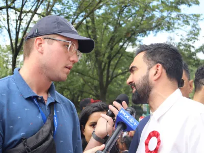 A student holding a microphone interviews a man. 