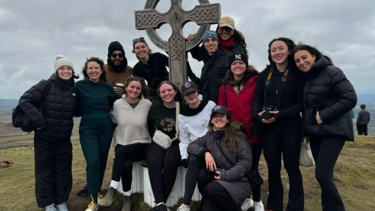 Students gathered around a stone cross. 