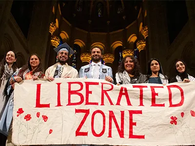 Seven Columbia students hold a white banner with "Liberated Zone" written in red. 