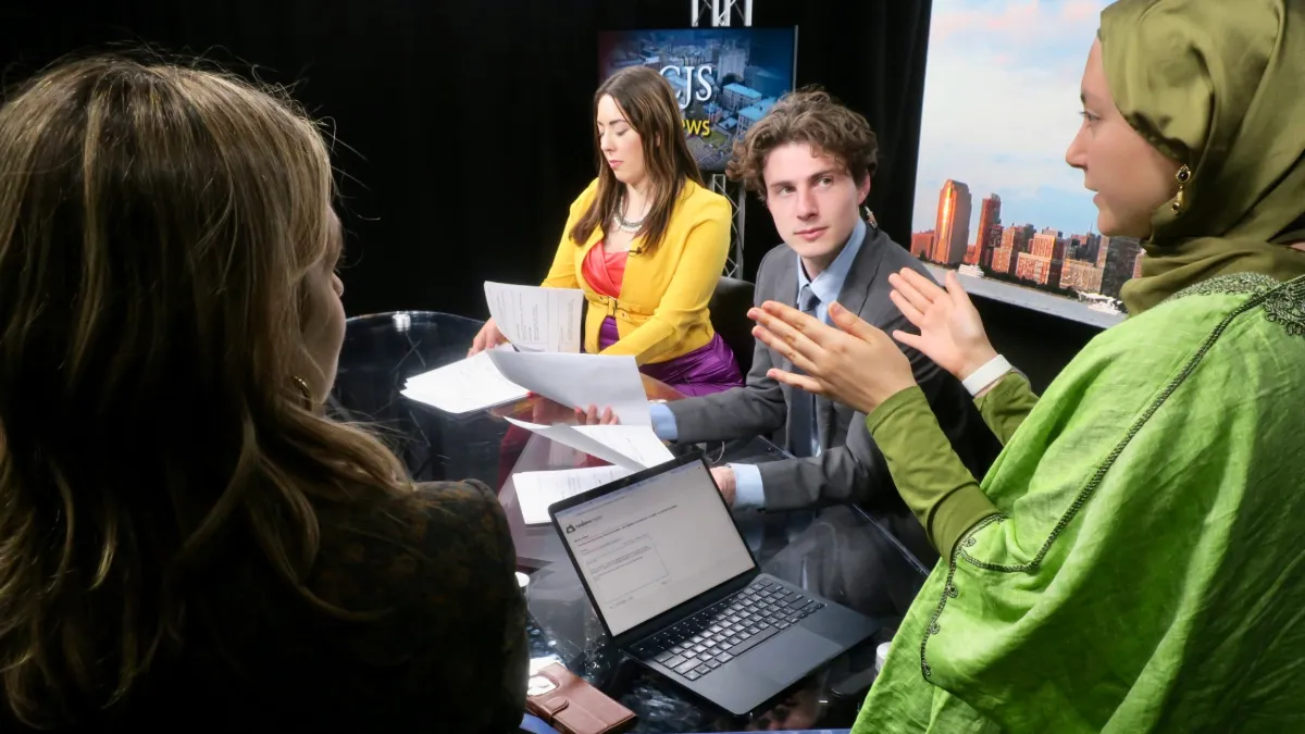 Students gather around a newsdesk. 