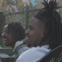 Two young men laugh besides each other in a backyard. 