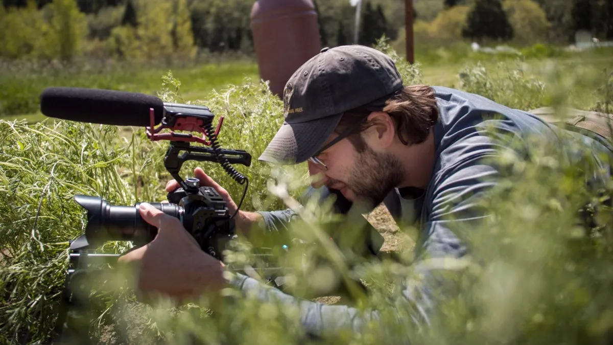 Nathan Keowen, M.S. ’26, records video footage with a camera in an open field.