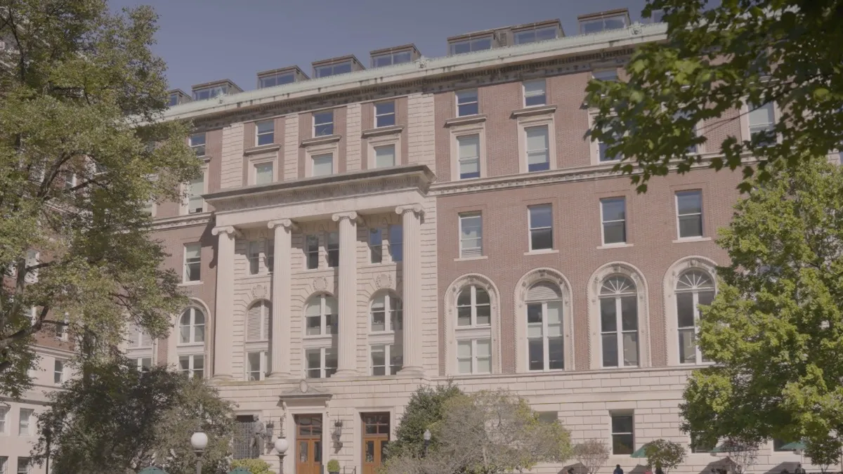 Historic brick building with a classical facade and surrounding trees.